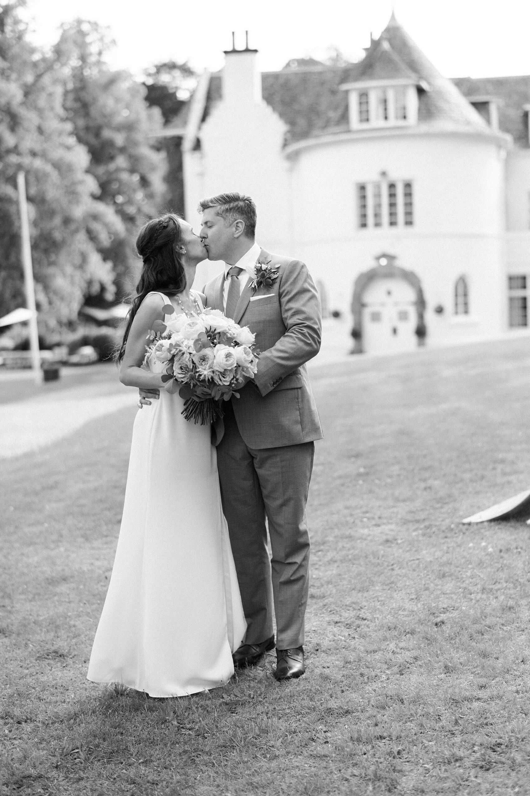 newlyweds kiss in front of castle at Scotland wedding 