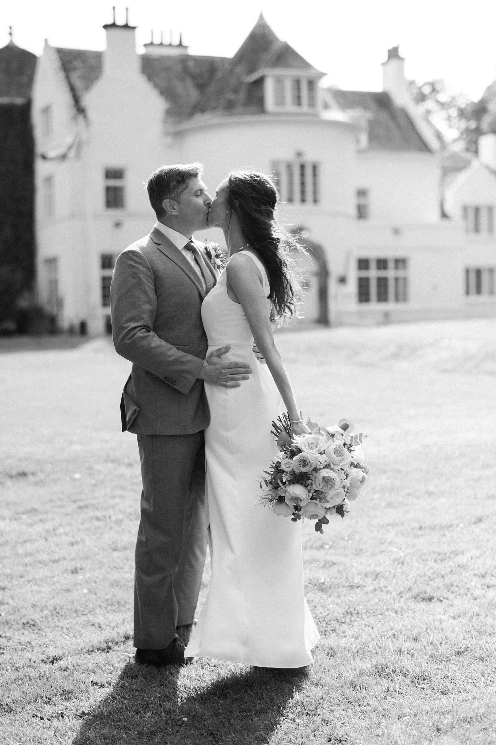 newlyweds kiss in front of castle 