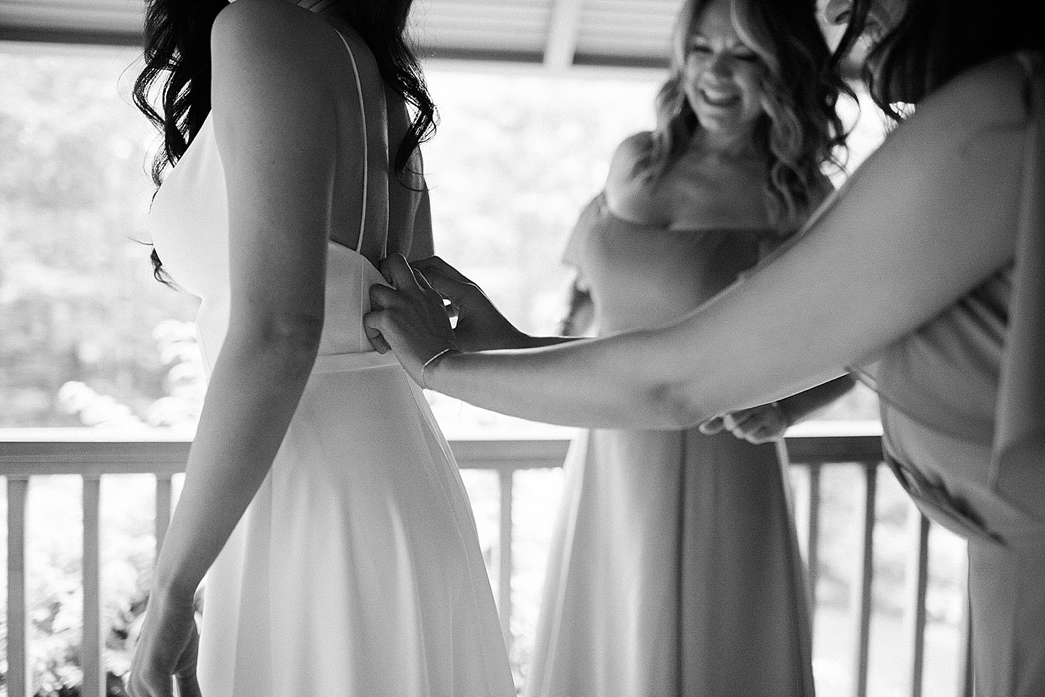 bridesmaids help bride into dress
