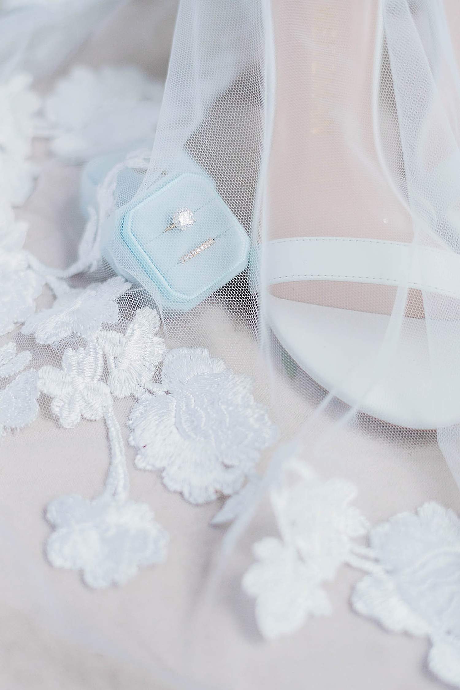 lace of veil over rings and bride's shoes
