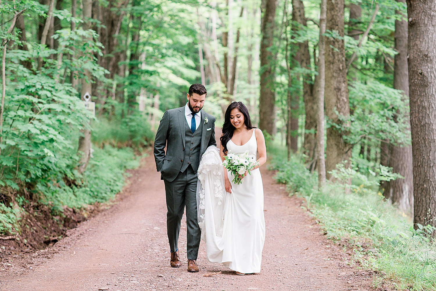 bride and groom walk path in woods at Deer Mountain Inn wedding