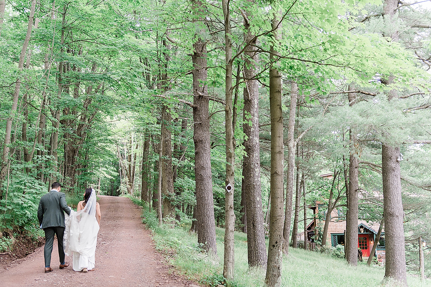 bride and groom walk together on path in woods