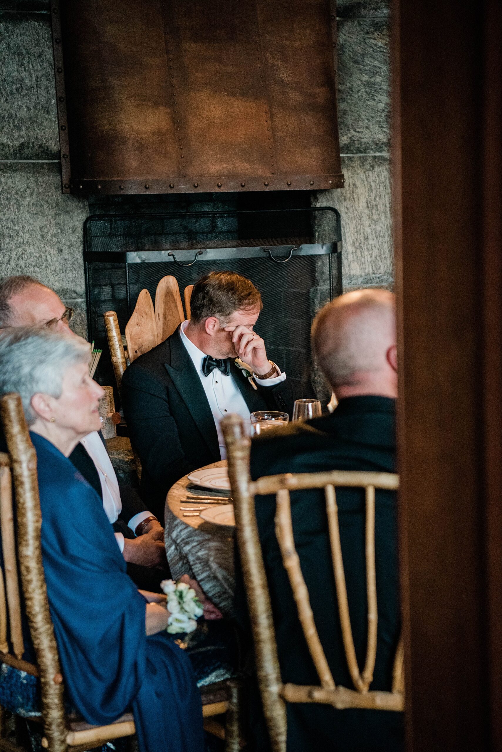 groom wiping tears during wedding reception at Lake Placid Lodge