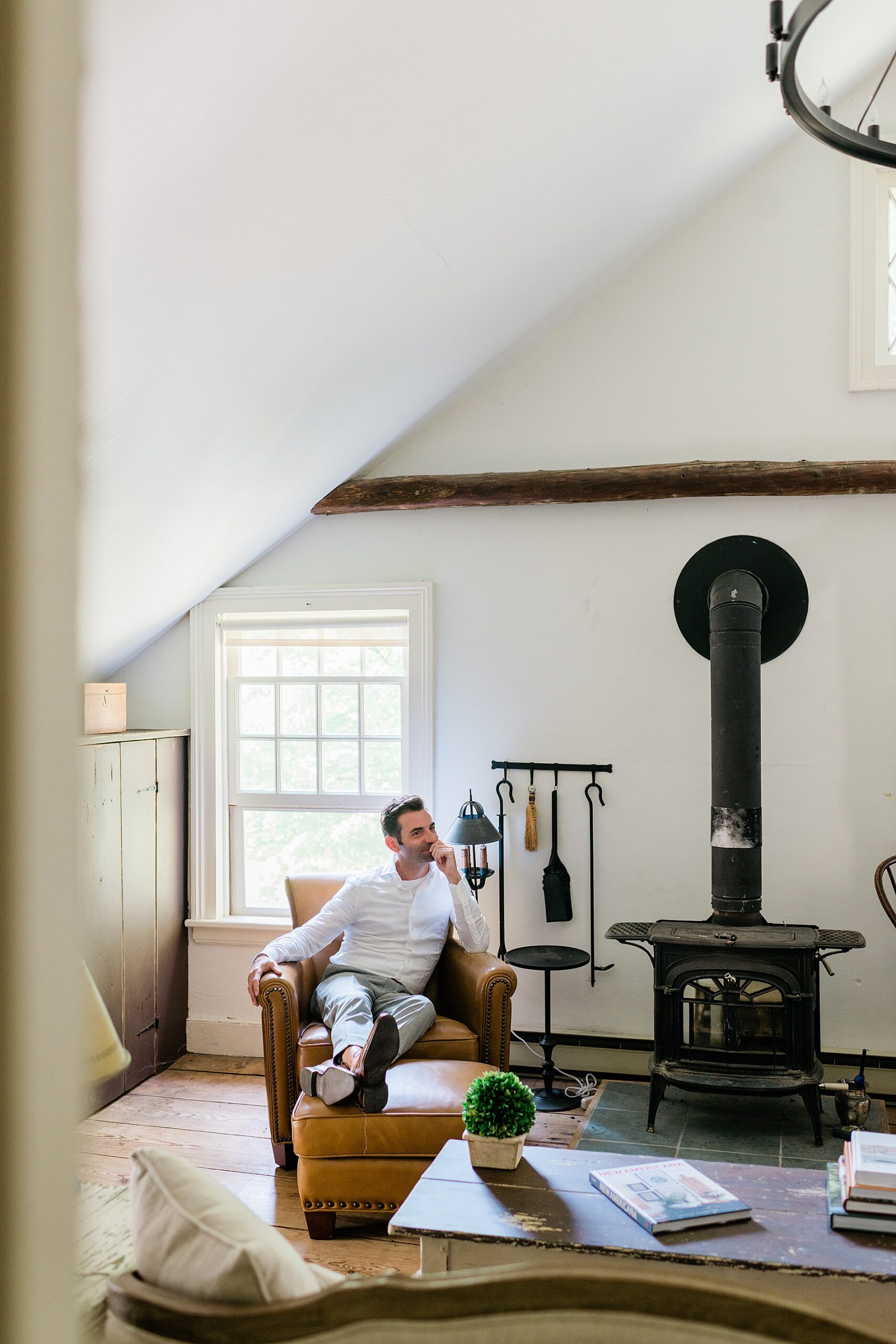 groom sitting in chair by wood burning stove at private estate