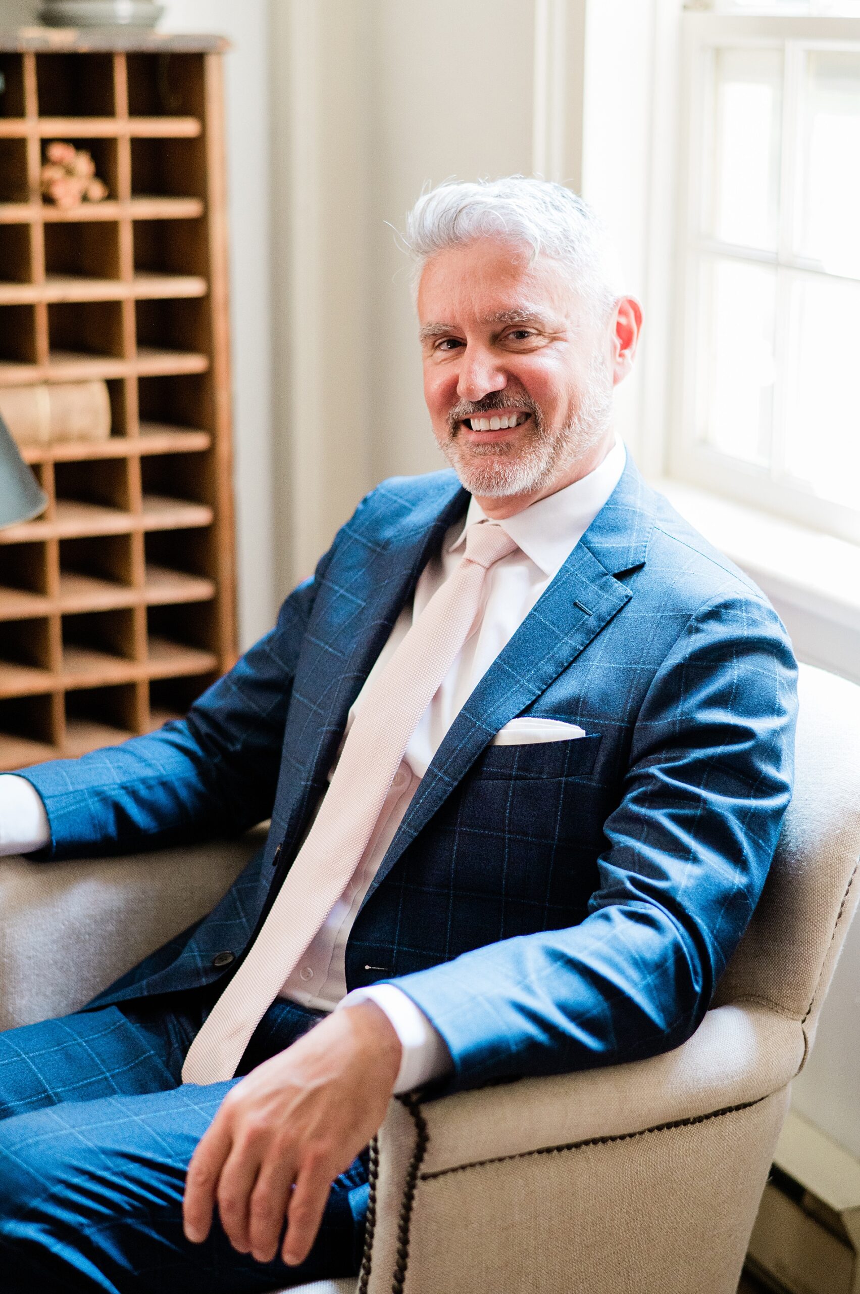 man in blue suit sits in chair