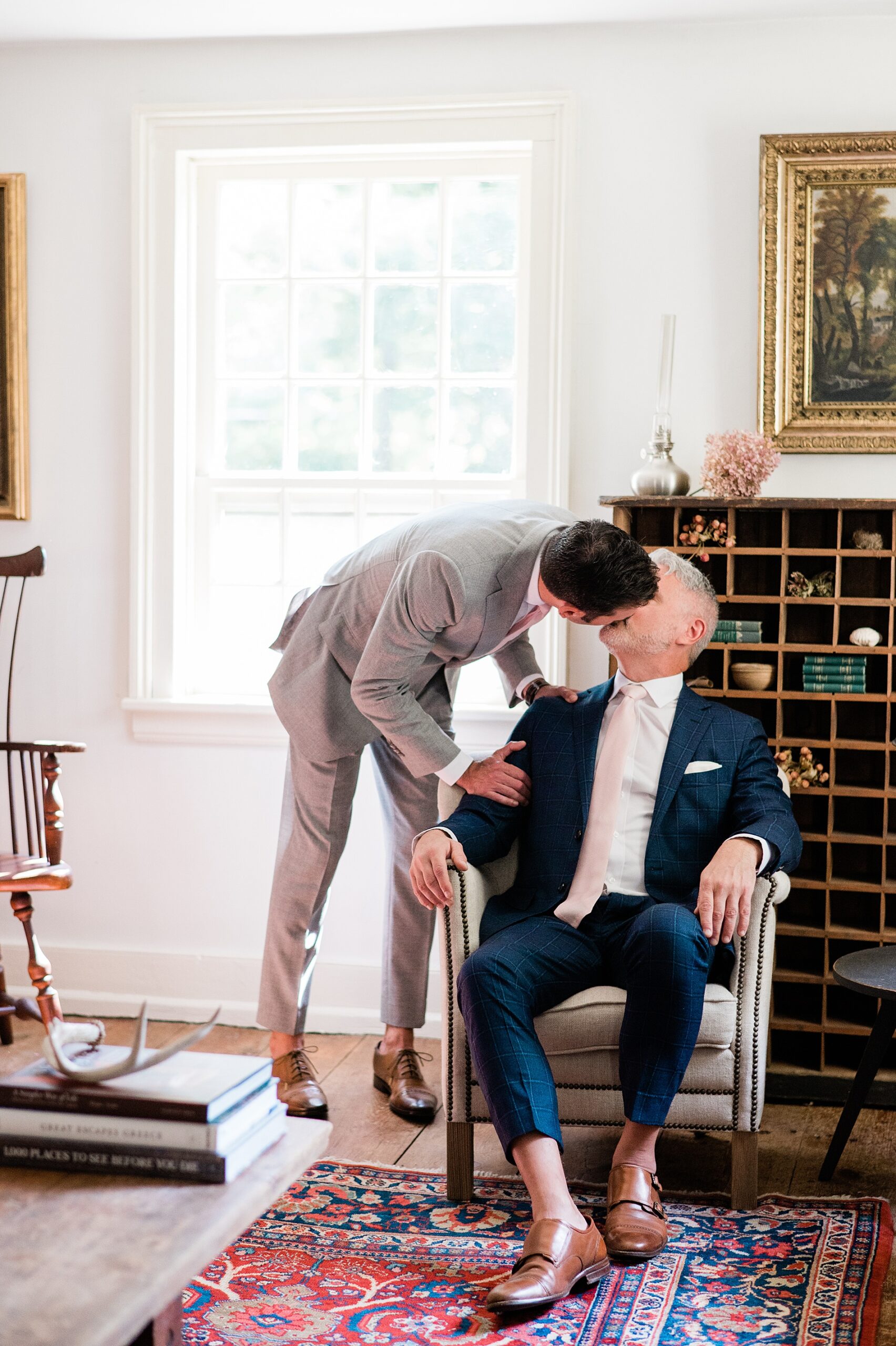 grooms kiss in their home as they ready for their wedding