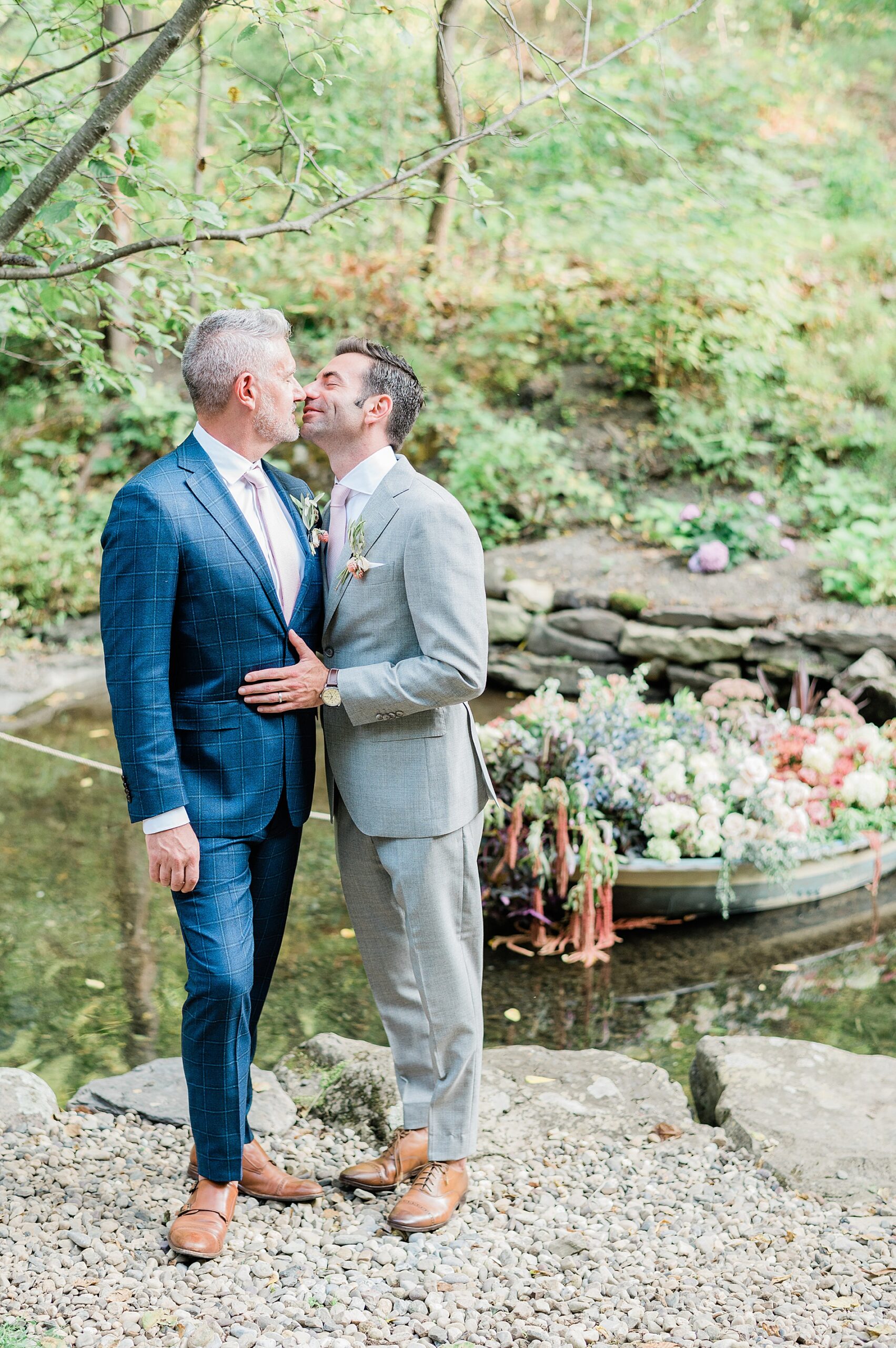 couple kiss by creek bed with boat filled with flowers