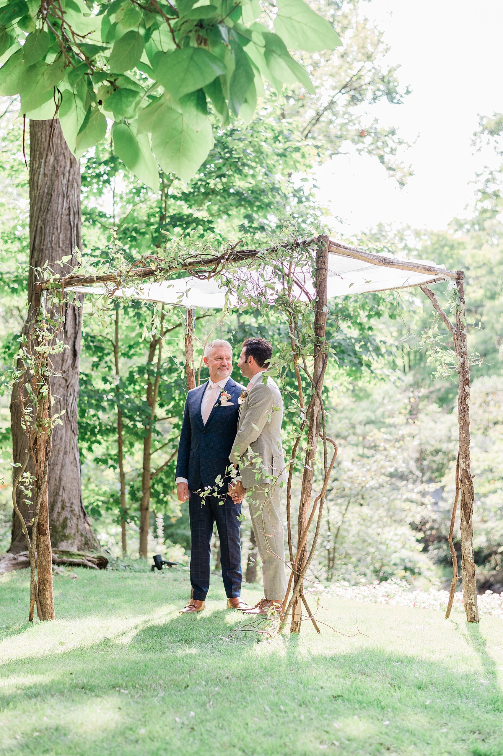 grooms at wedding ceremony under wedding arch