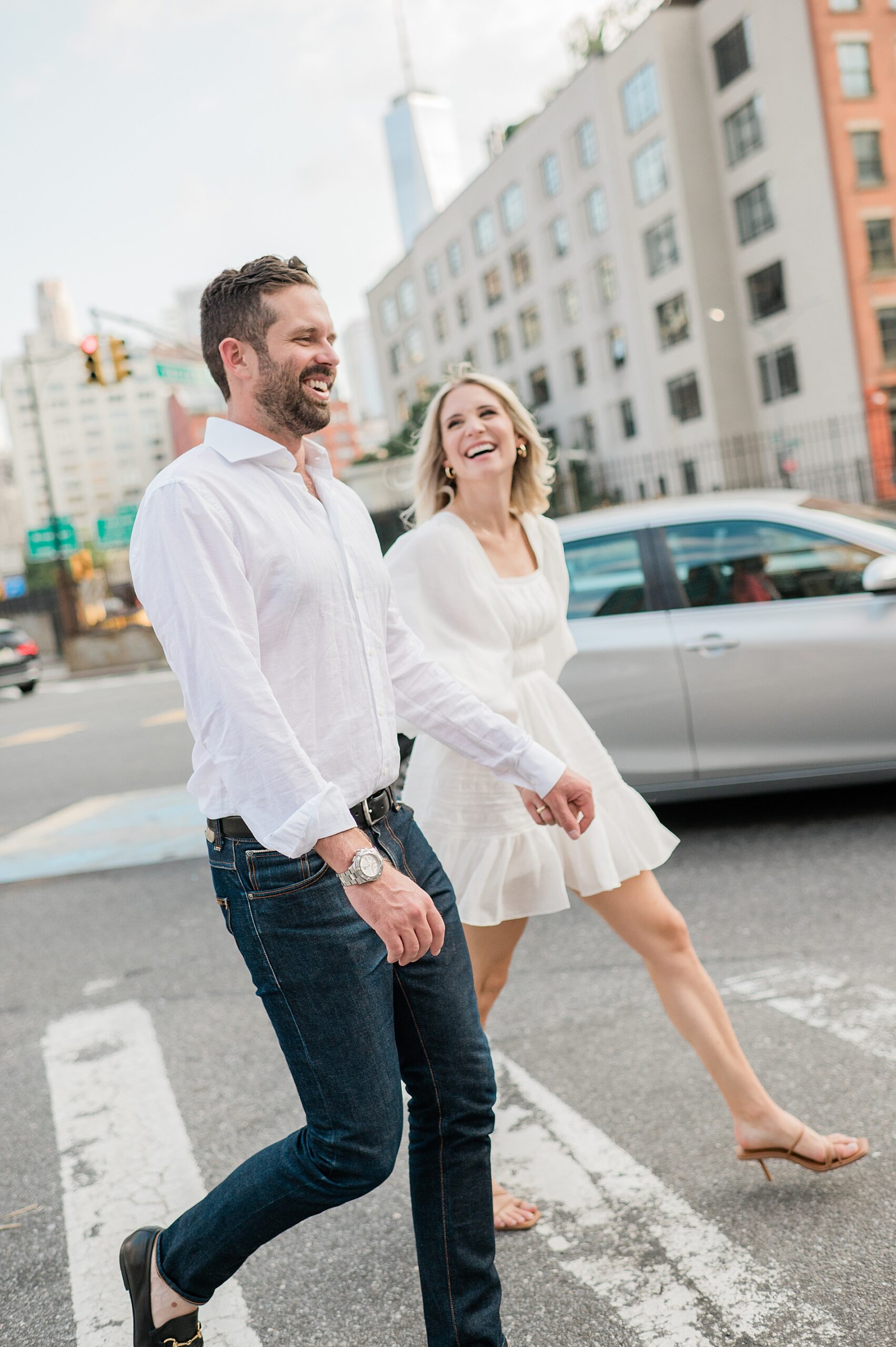couple laugh as they walk together crossing the street in downtown Manhattan