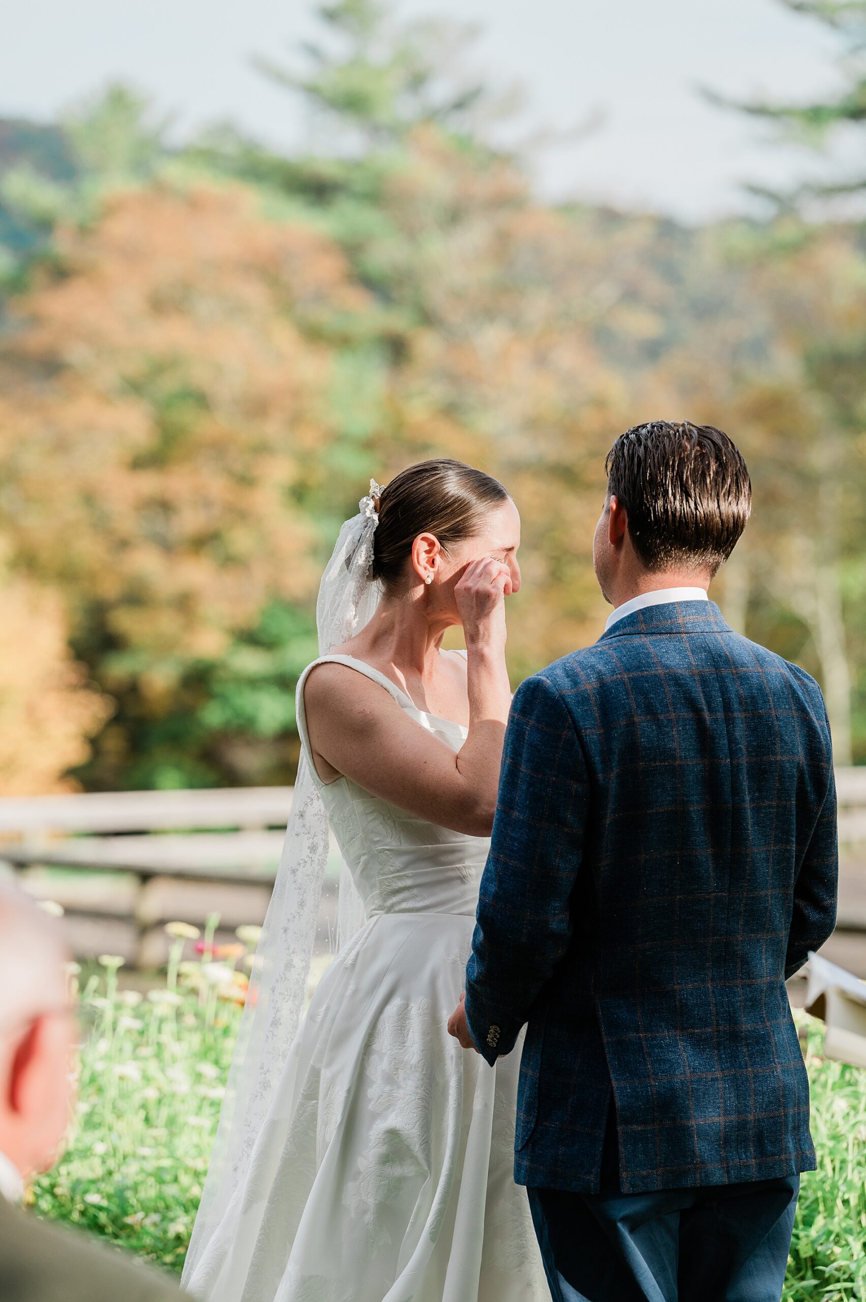bride wipes away tears during wedding ceremony.