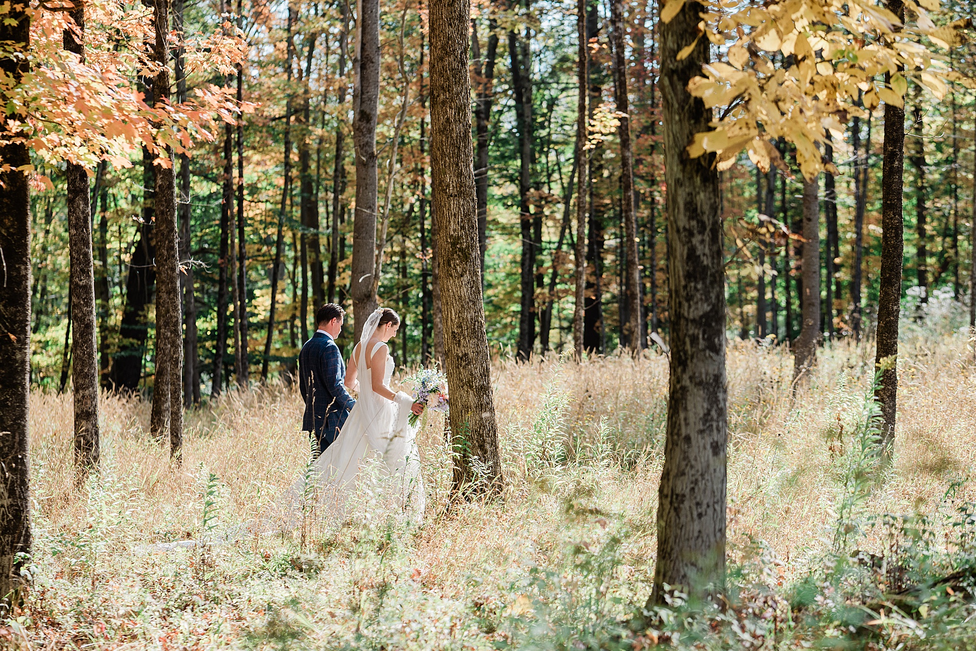bride and groom hold hands as they walk through the woods