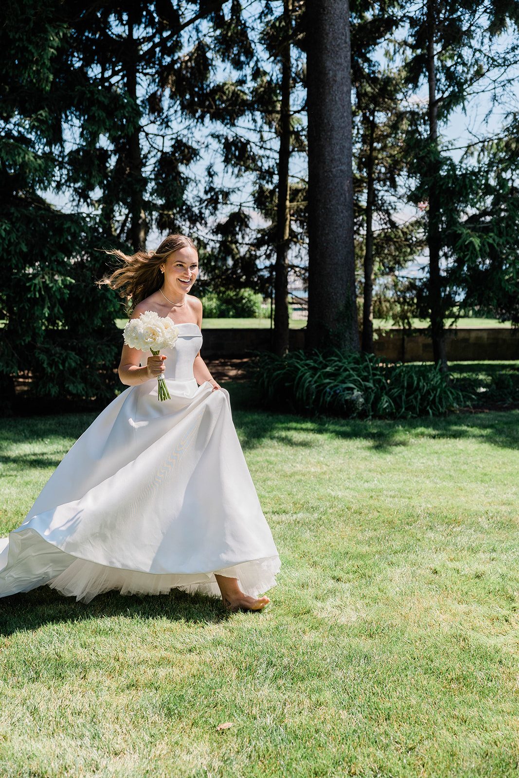 bride runs across lawn barefoot holding bouquet