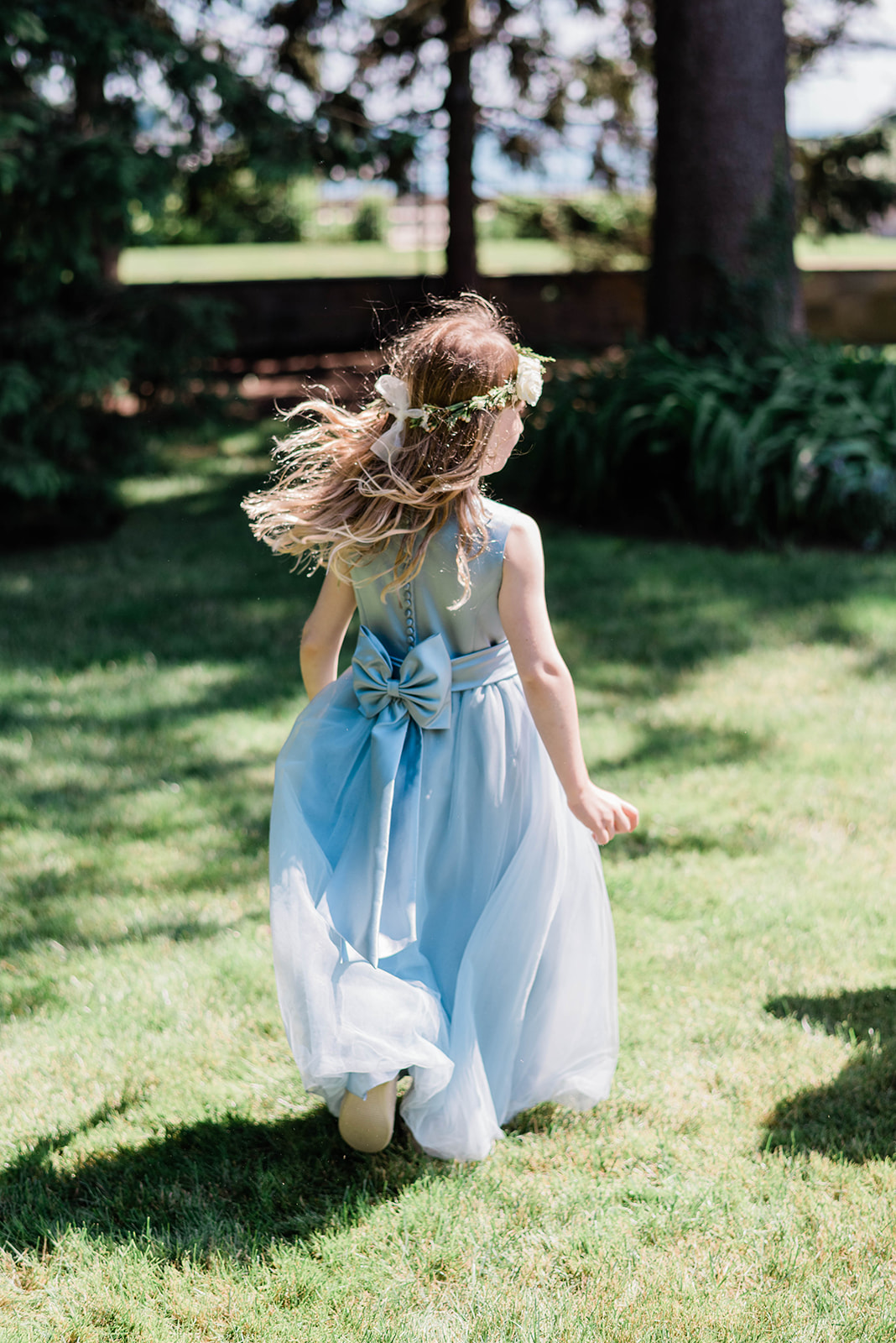 back of flower girl's dress as she walks across lawn
