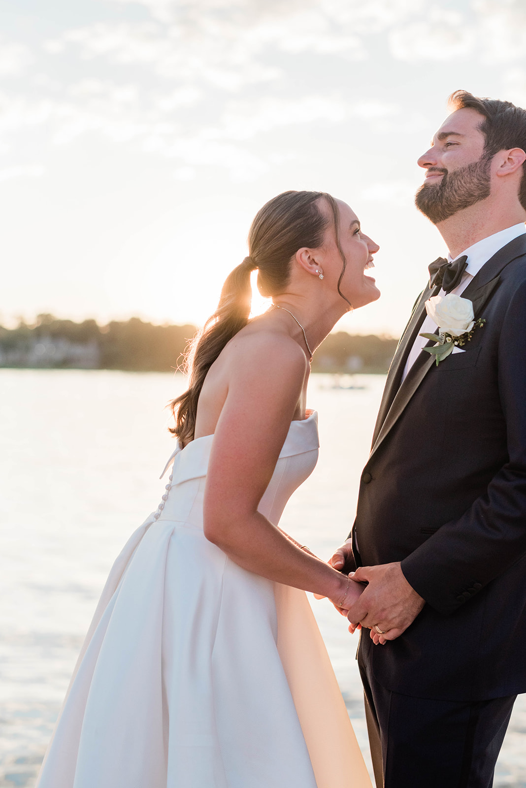 joyful and candid wedding photos of bride laughing with groom as the sun sets in the distance 