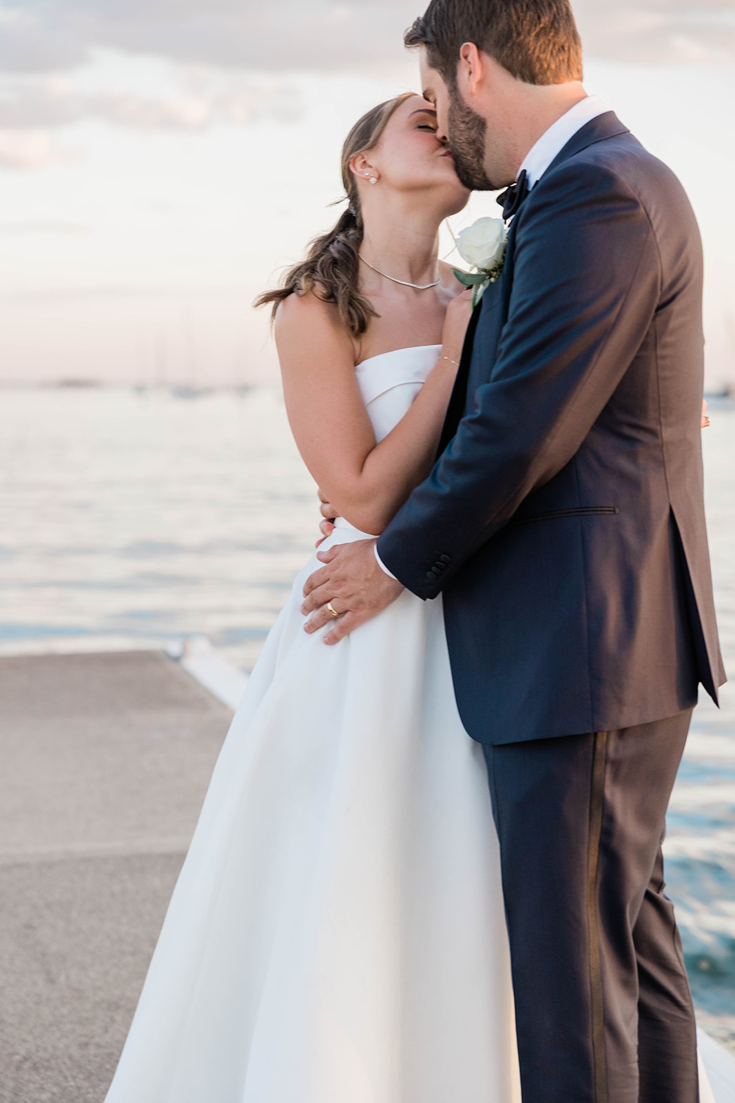 newlyweds kiss by the water after summer wedding ceremony 