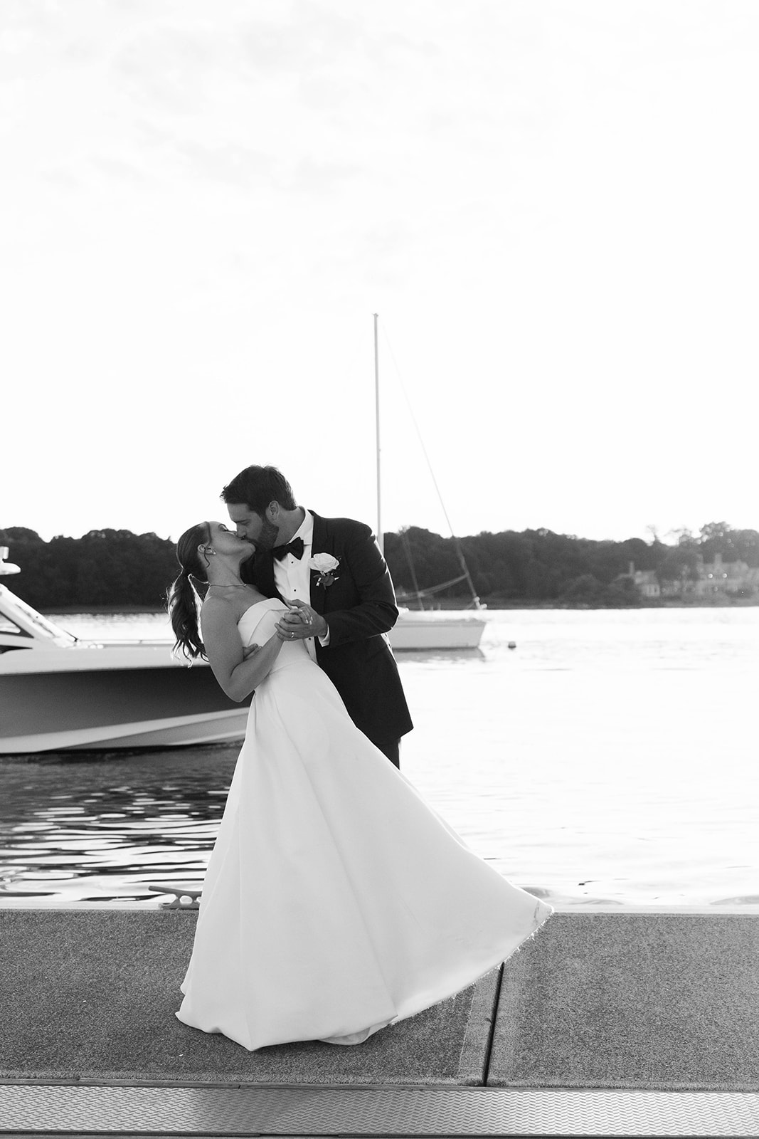groom kisses bride on the dock by the water at Riverside Yacht Club  
