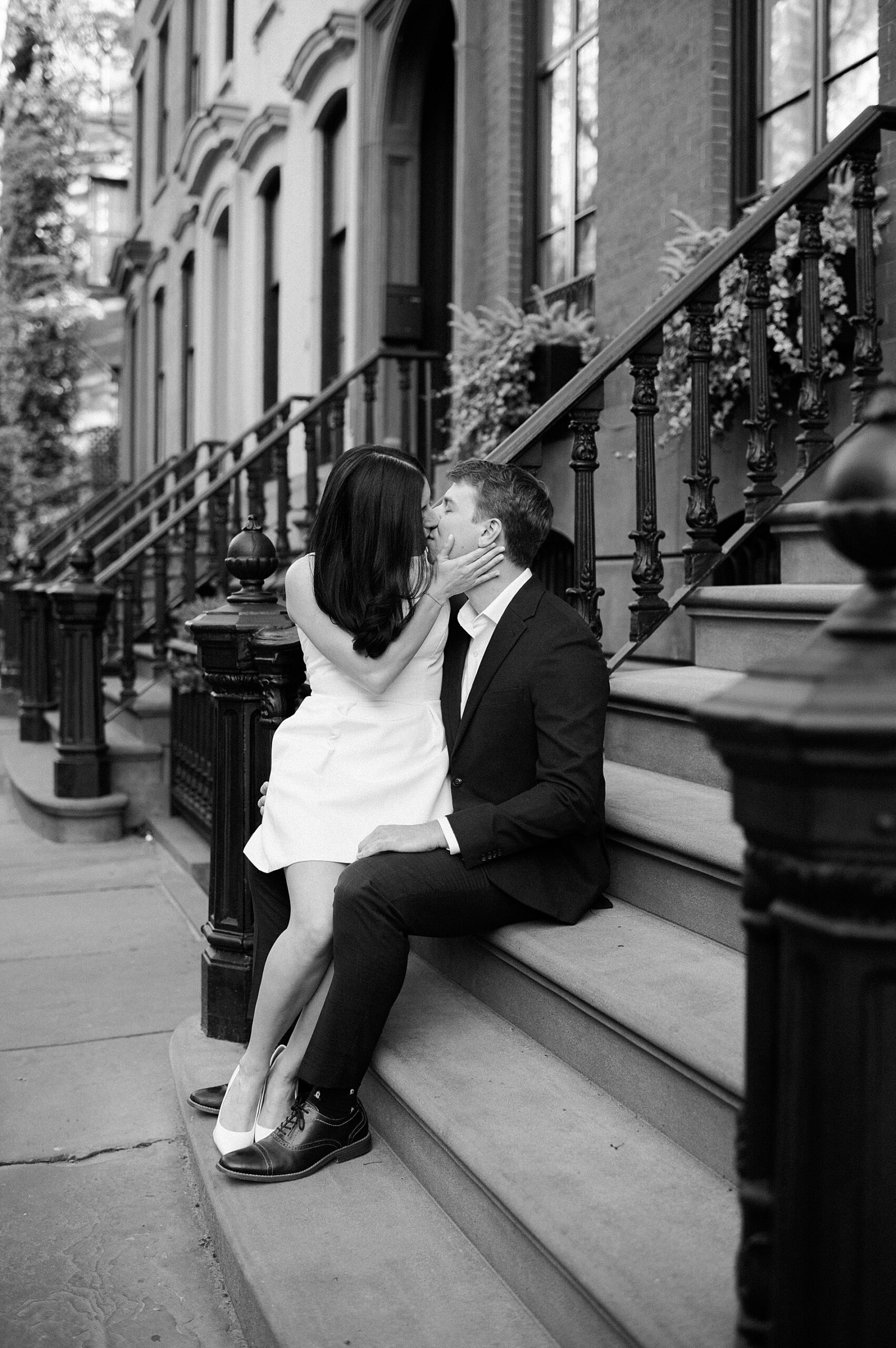 couple sit on stairs of building as they kiss