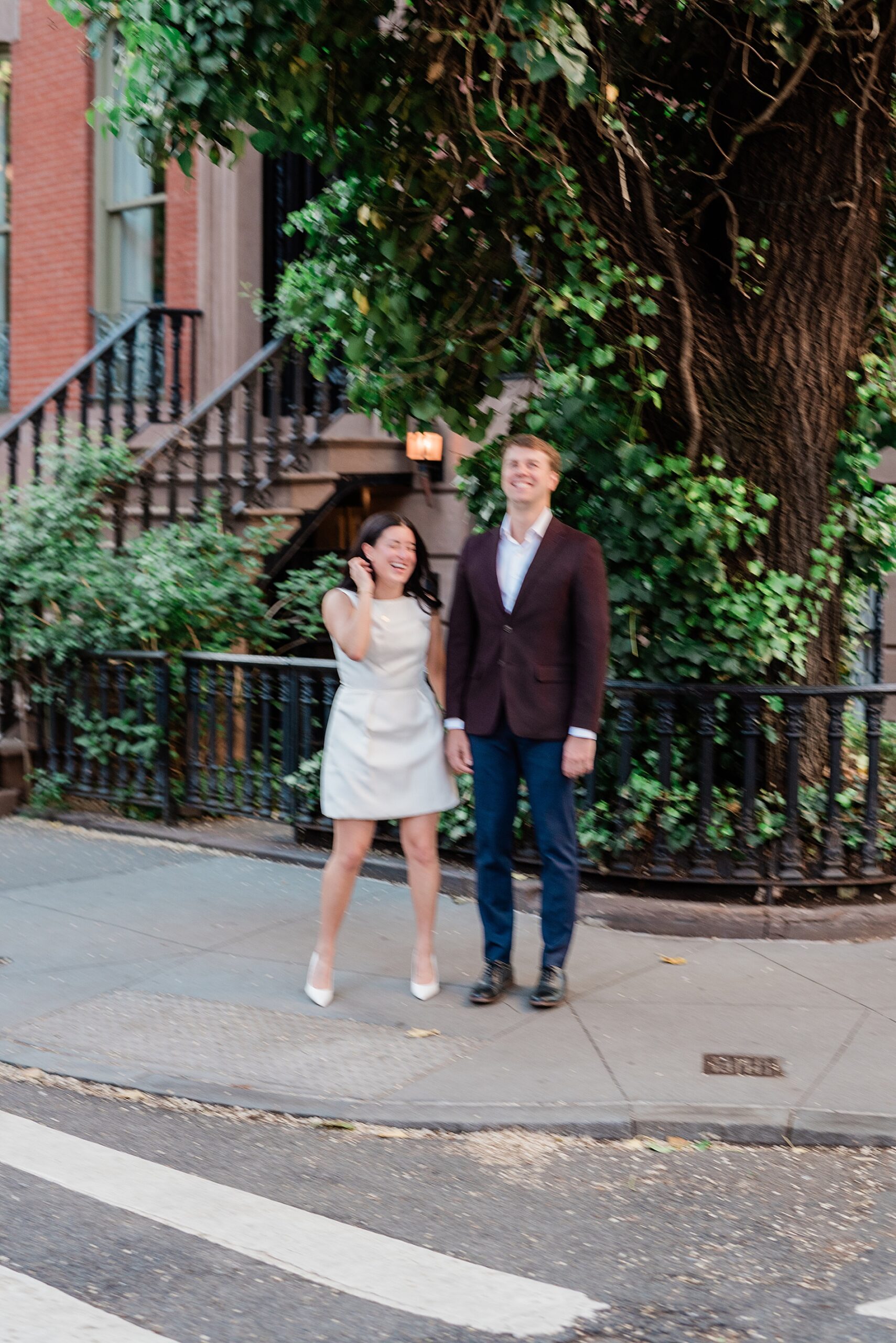 couple laugh as they stand at corner in their neighborhood of West Village