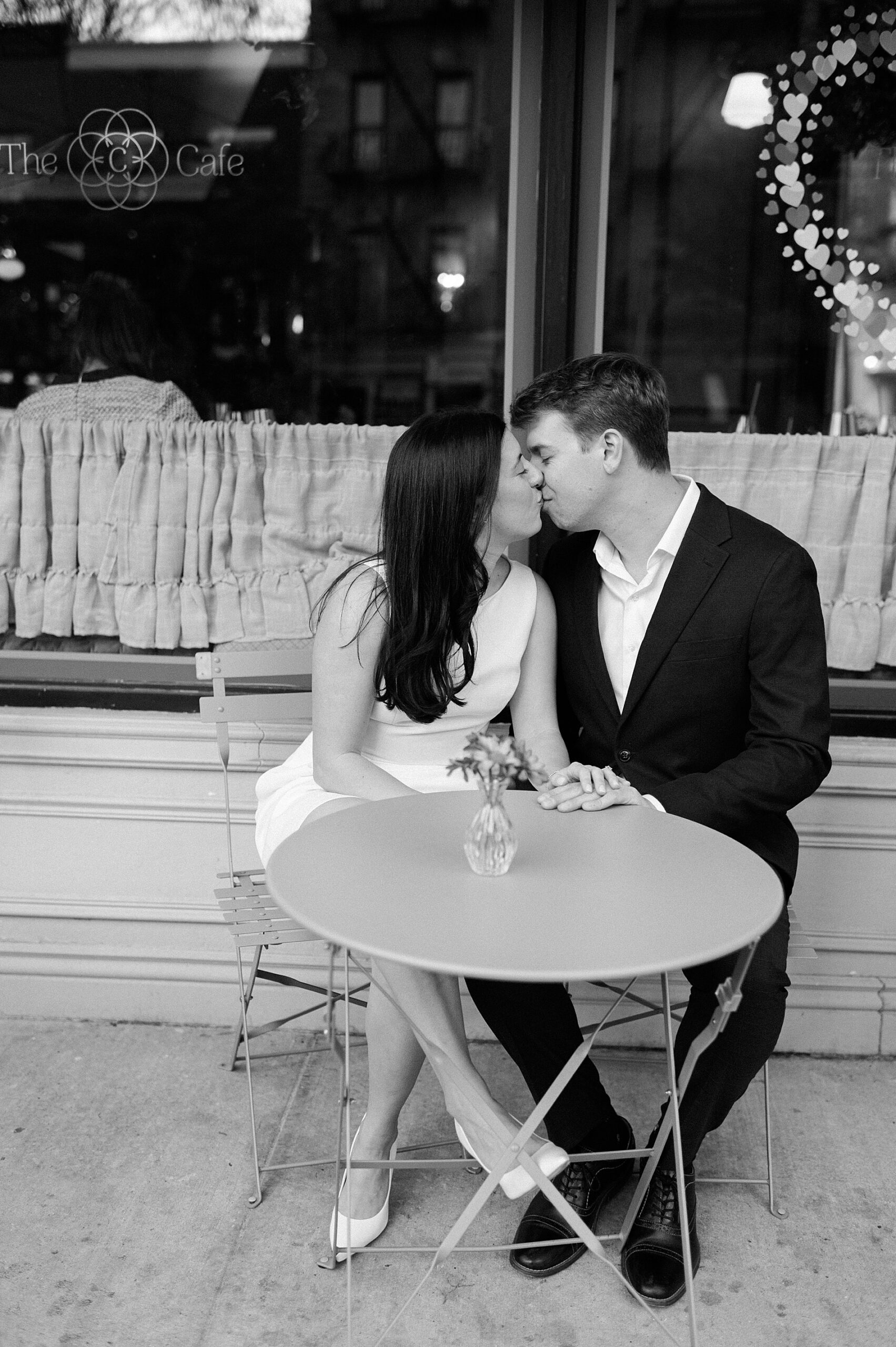 couple kiss while sitting at cafe table in NYC