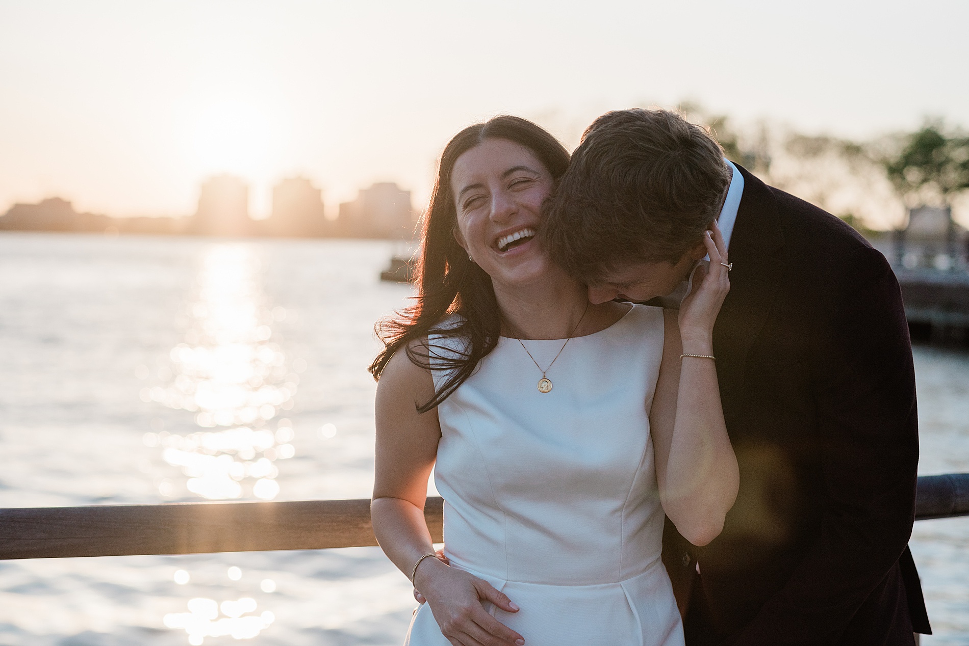 engagement photos of couple laughing by the water in NYC during sunset