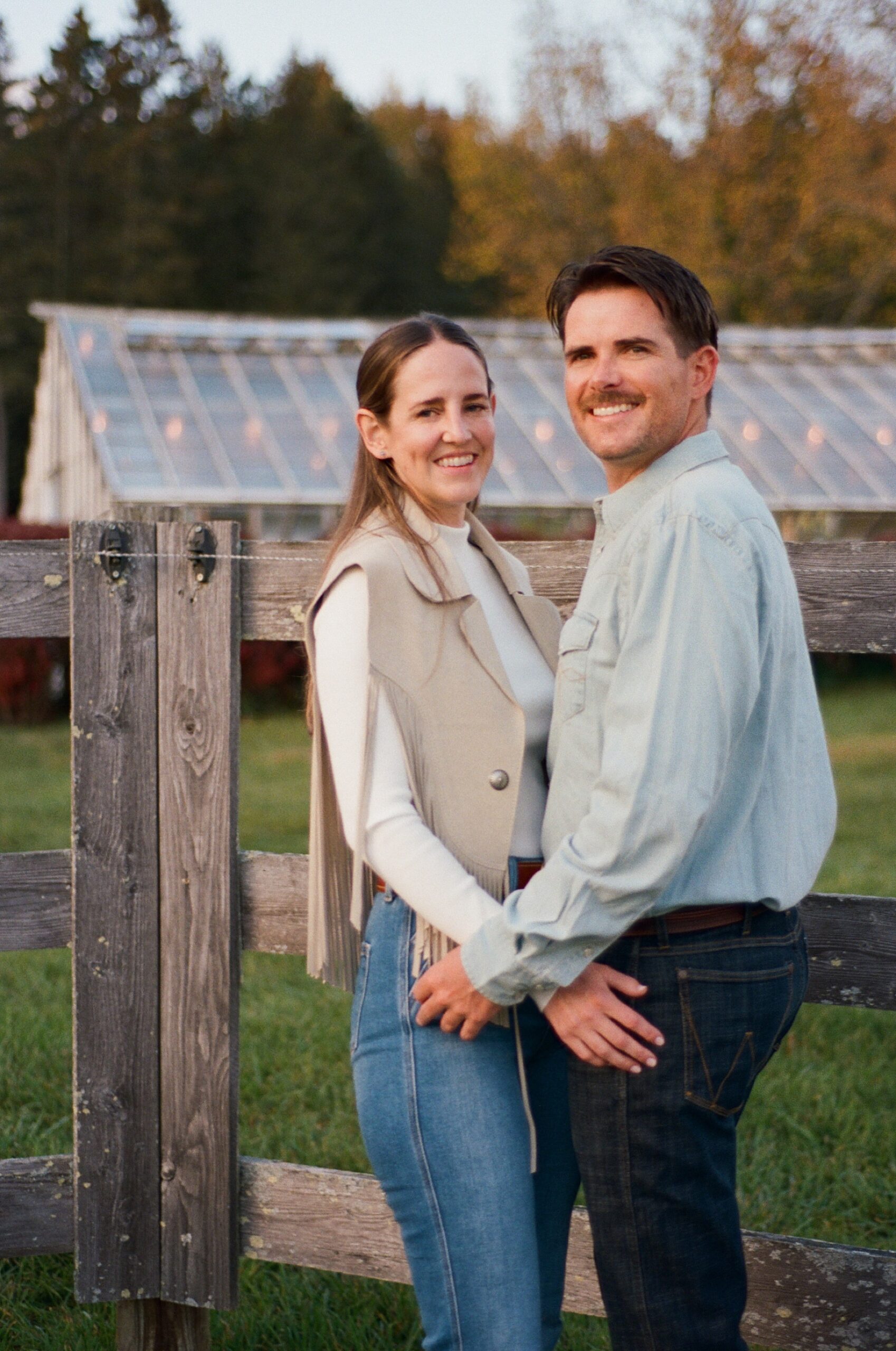 couple by fence on family land for wedding welcome party