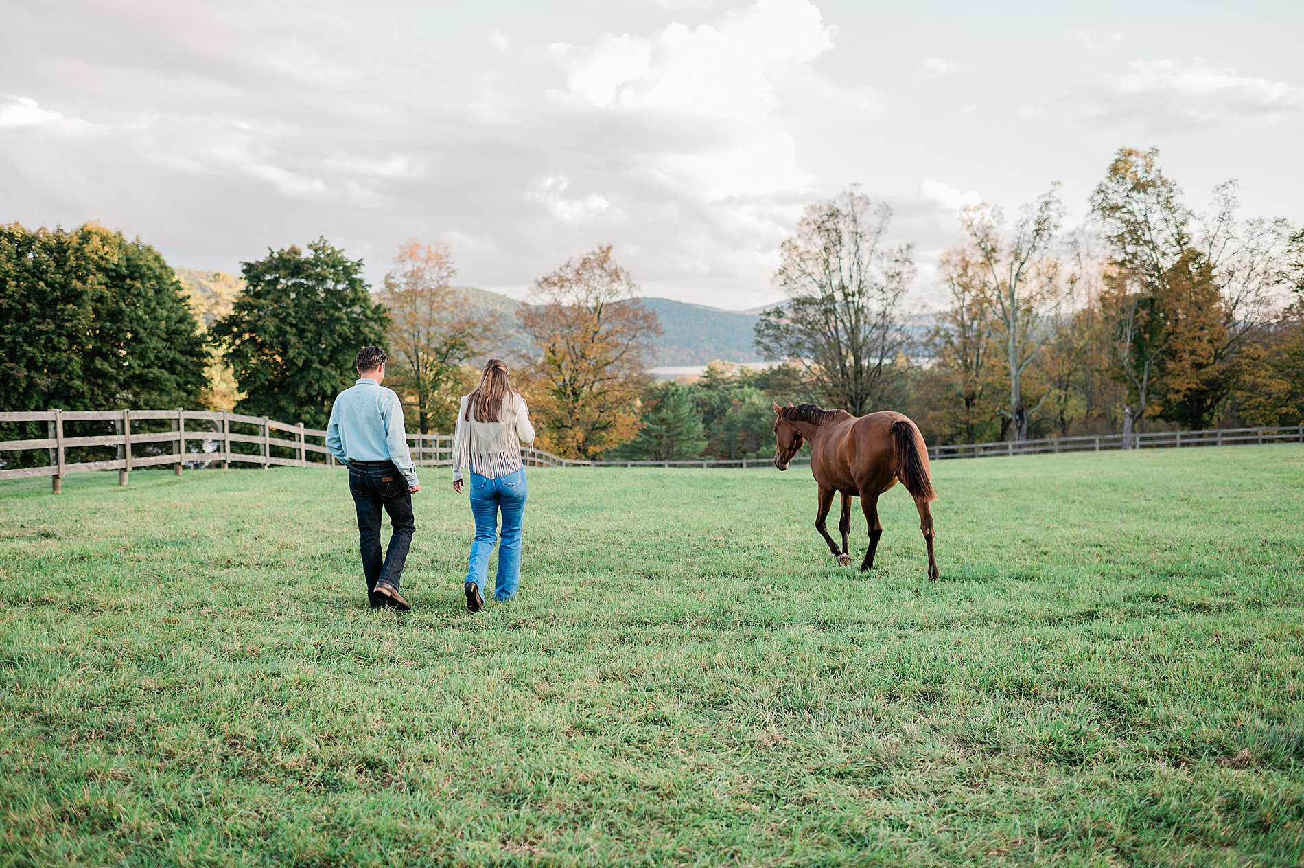 bride and groom-to-be walk along property next to horse before wedding welcome party
