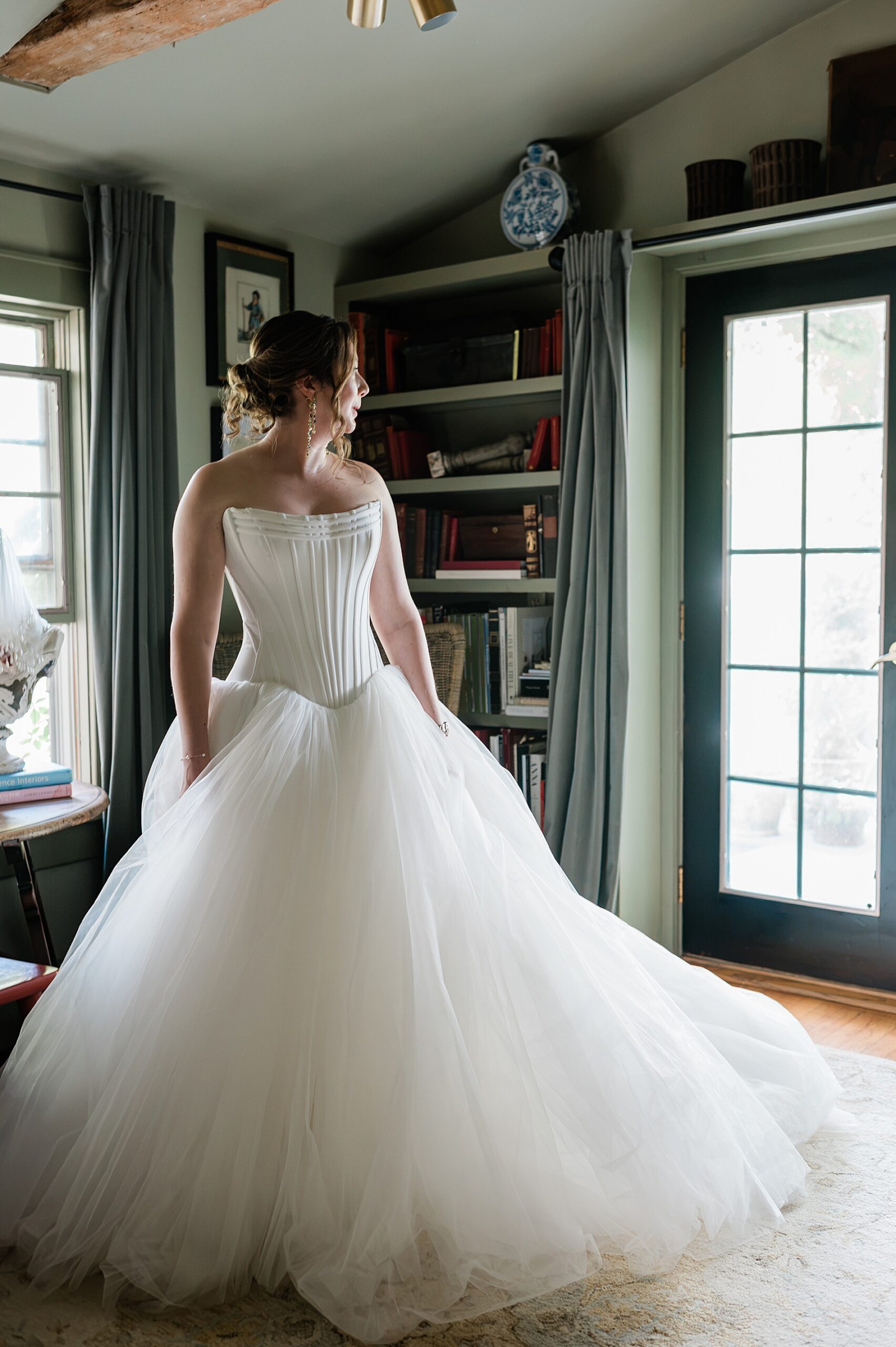 bride in wedding dress looking out window