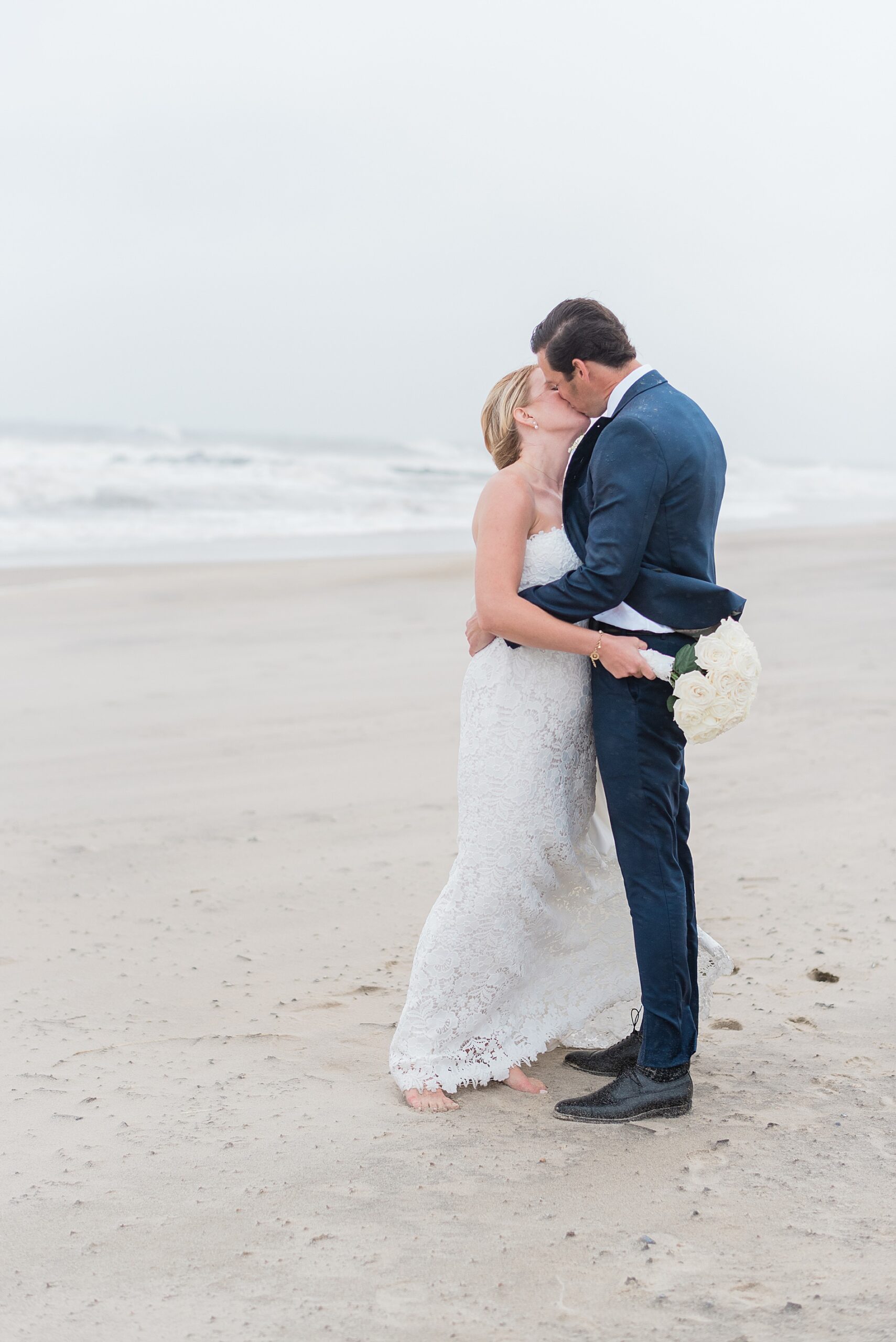 newlyweds kiss in the rain on Jersey shore