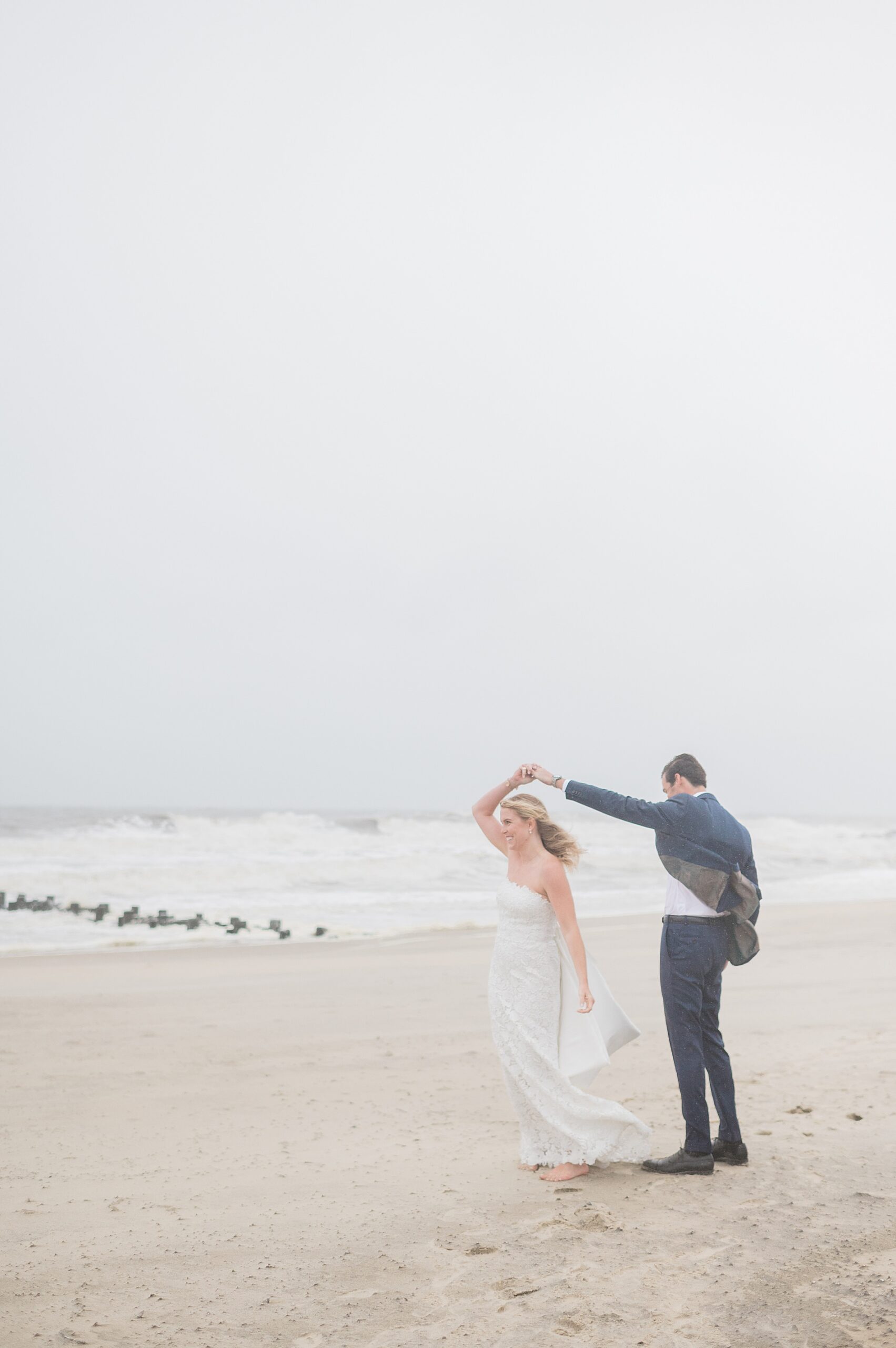 husband twirls bride on the beach from Rainy Spring Lake Wedding