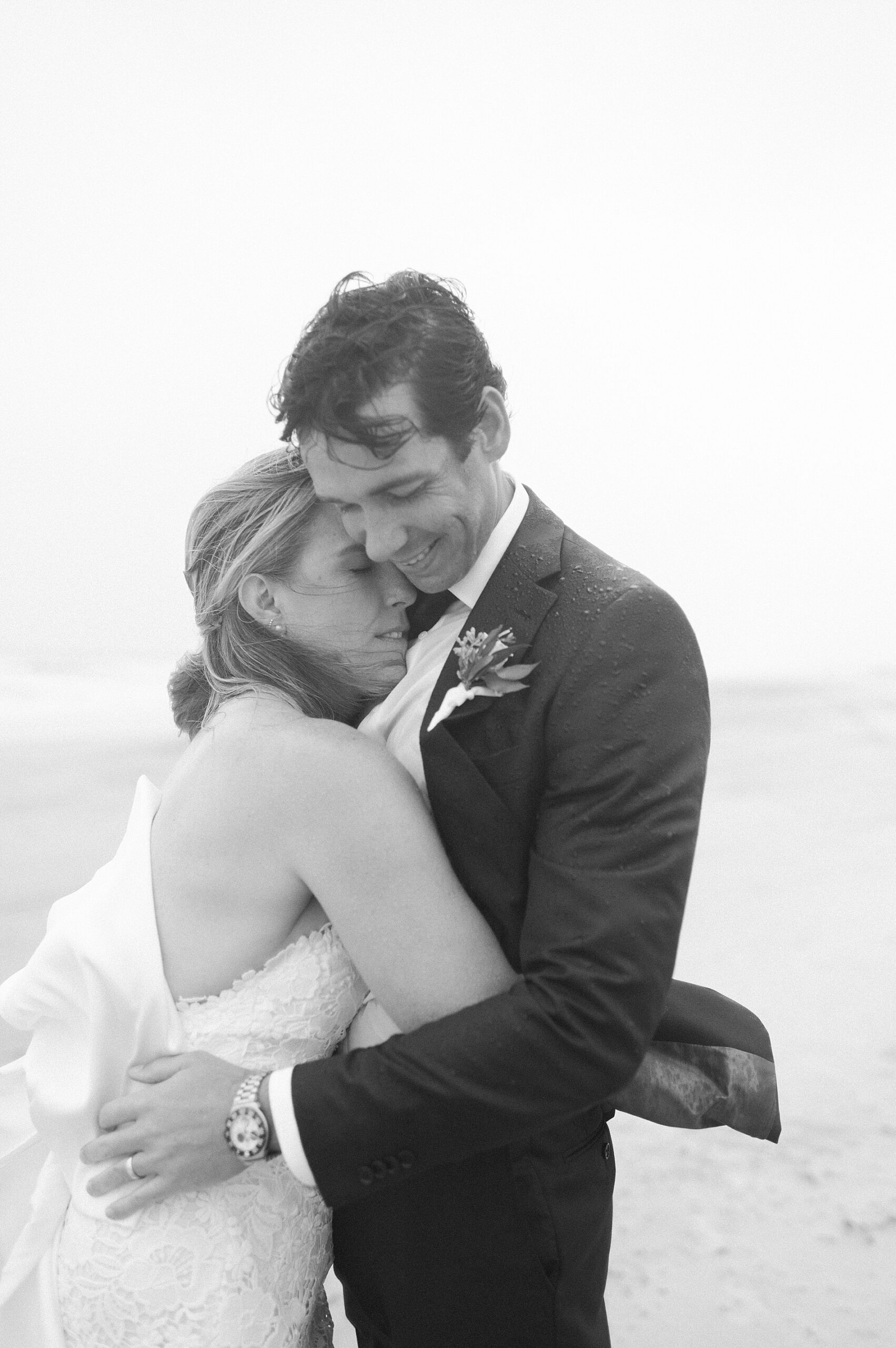 couple embrace on the beach in the rain
