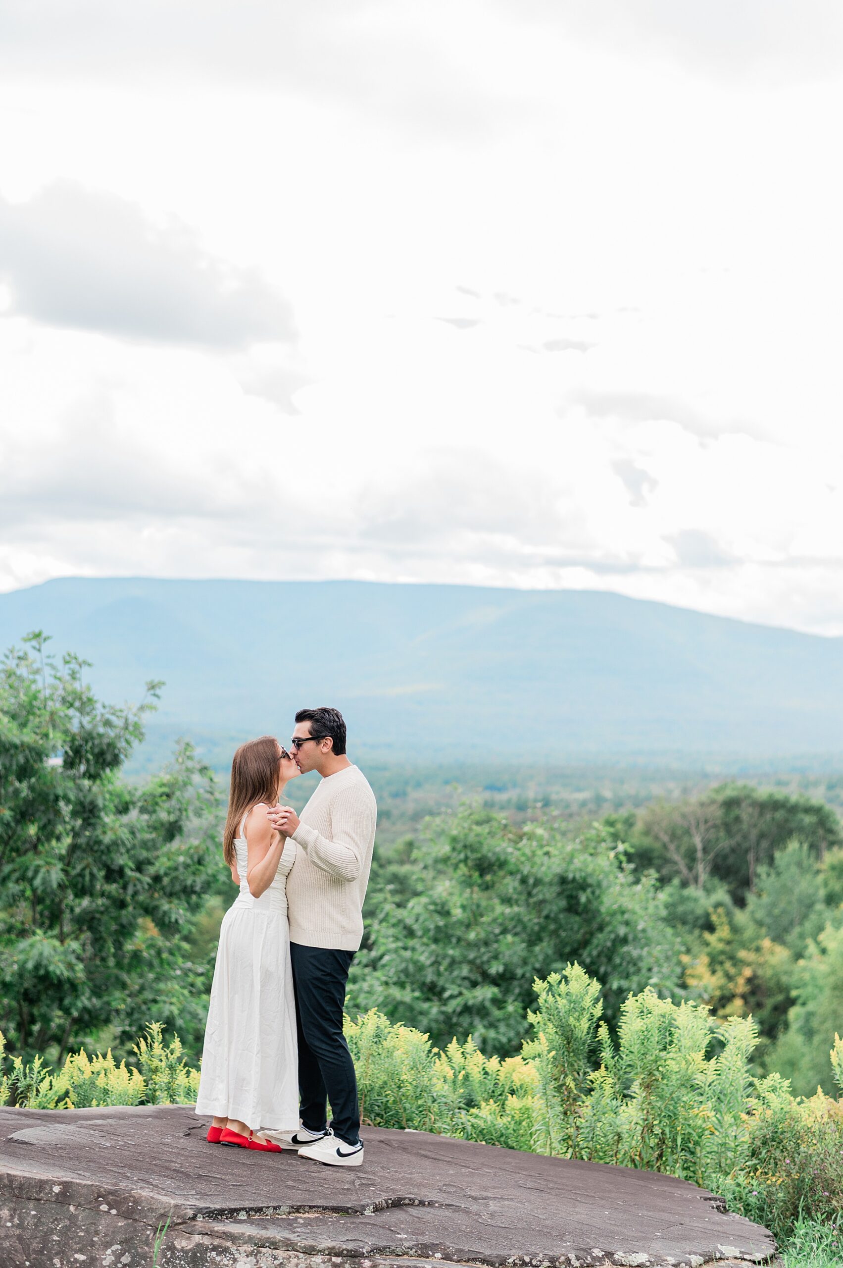 newly engaged couple kiss on rock overlooking Catskill mountains 