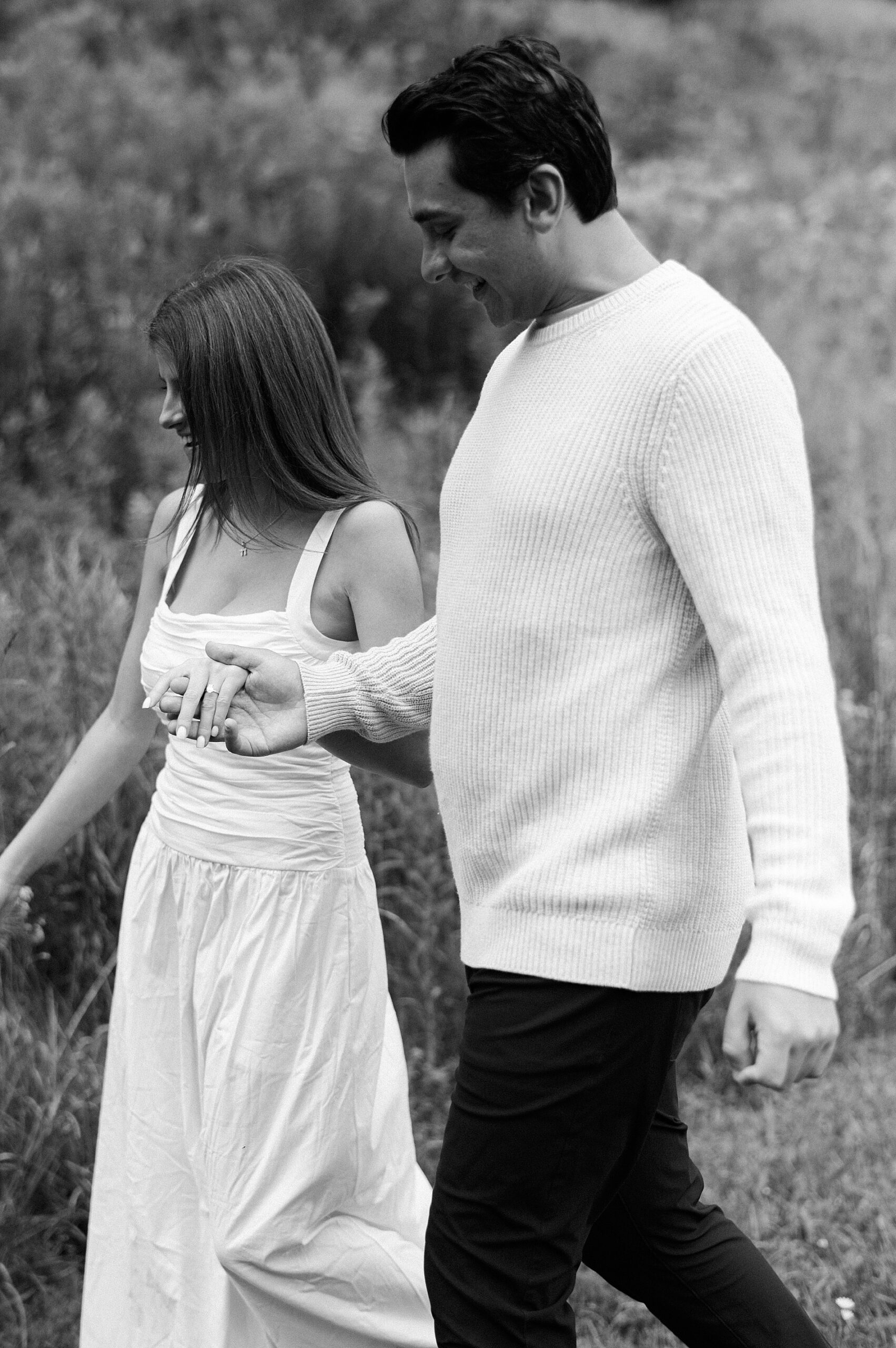 man holds fiance's hand as they walk down hill 