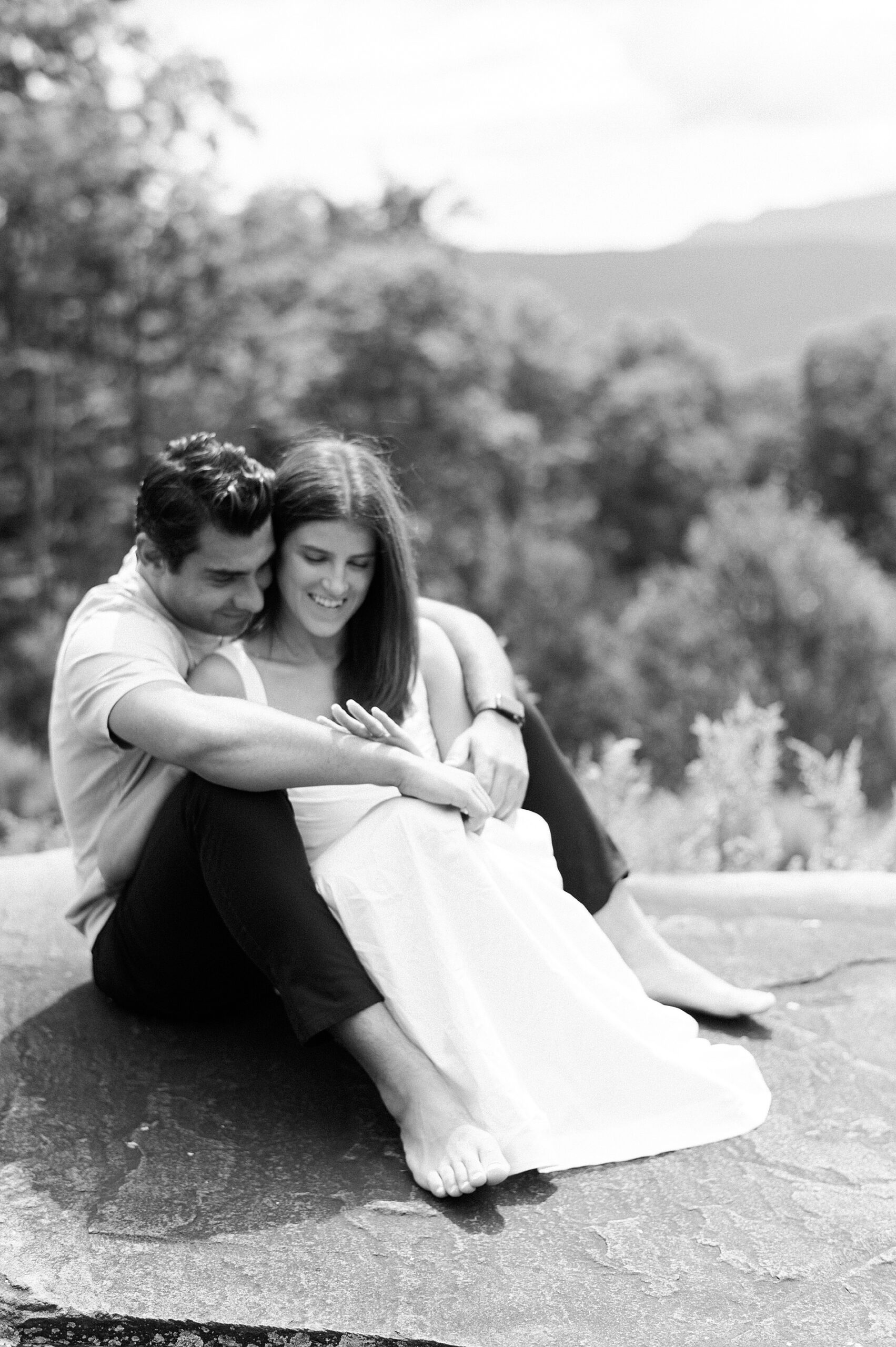 couple sit together as woman admires her new engagement ring 