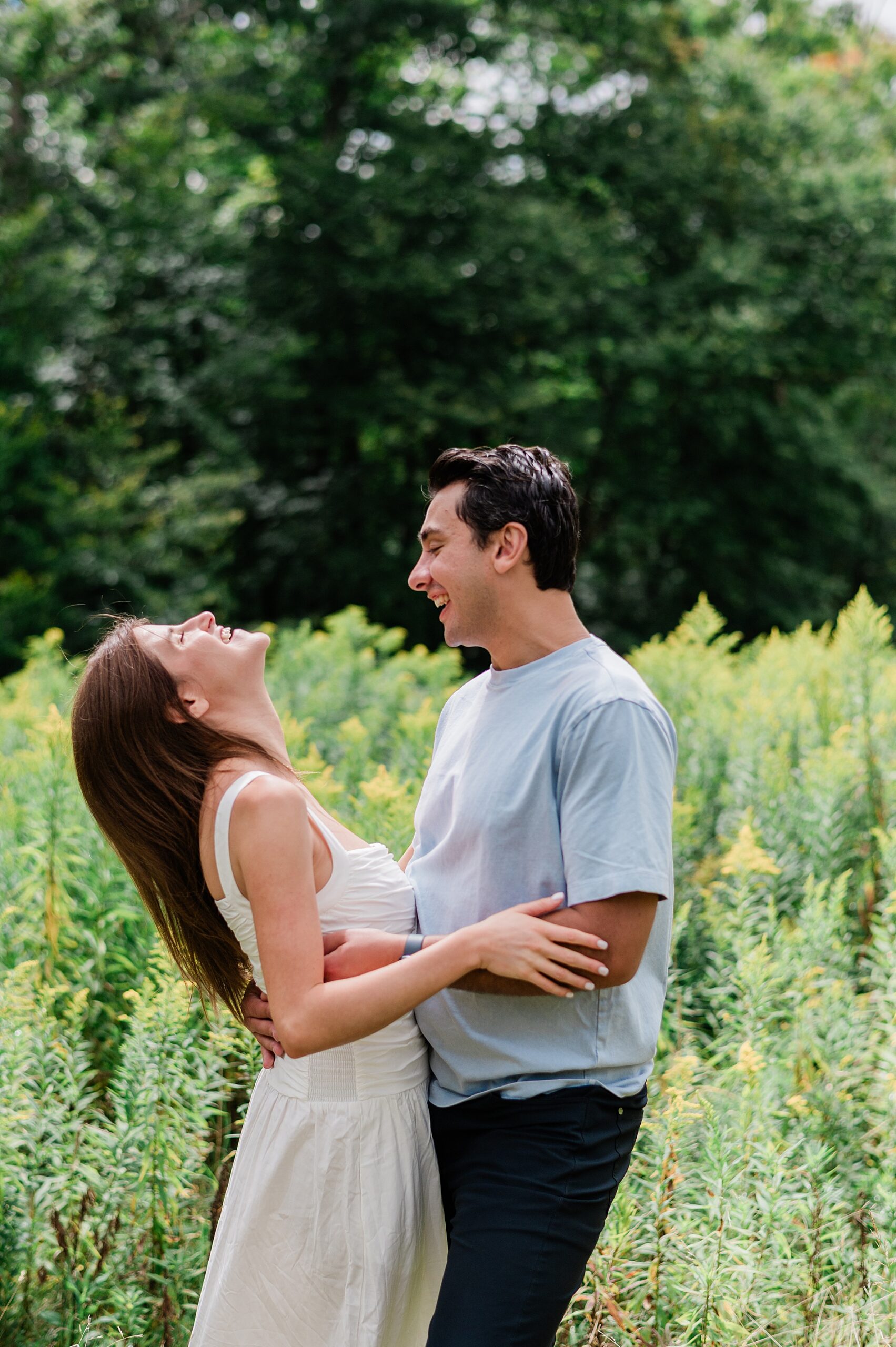 candid portraits of newly engaged couple laughing in field of wildflowers 