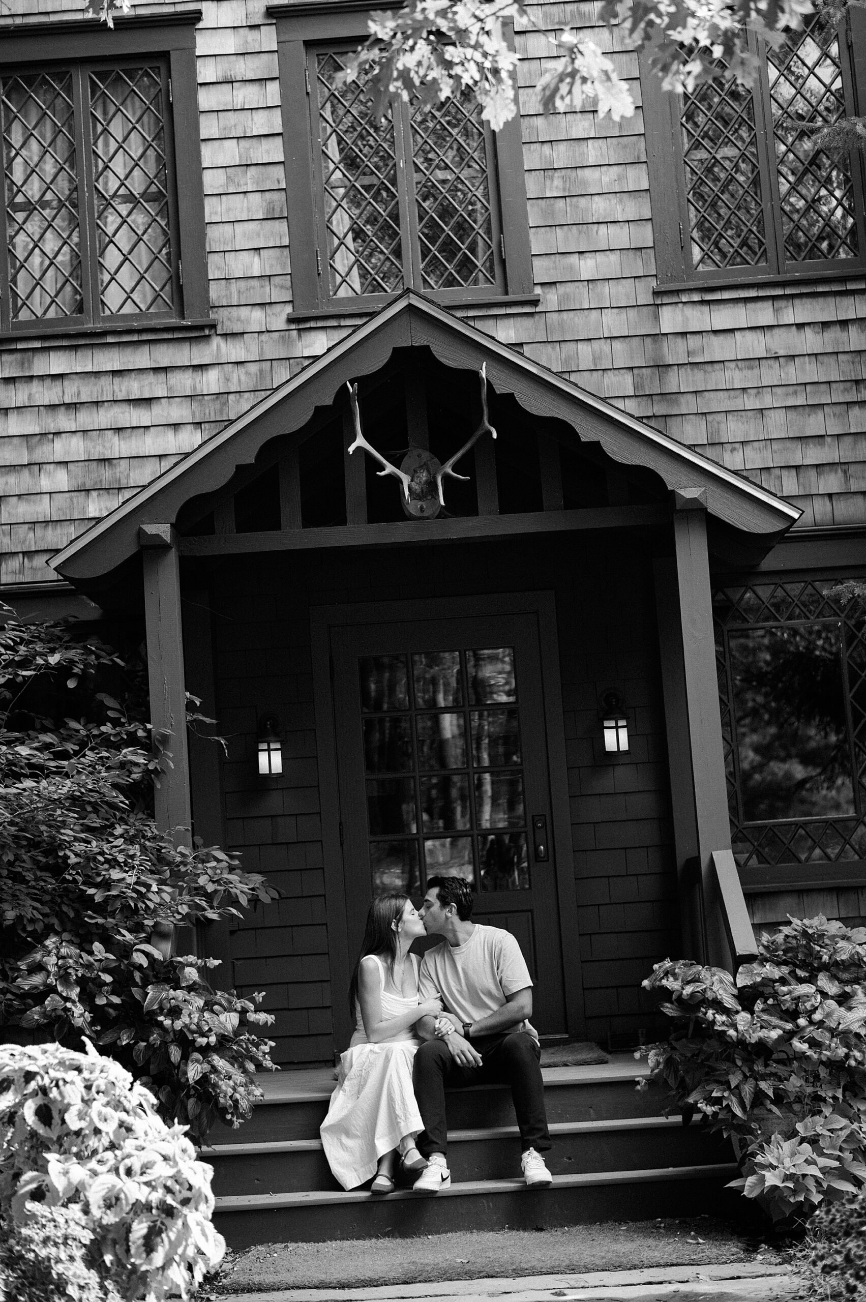 couple kiss on steps of building at Deer Mountain Inn in NY